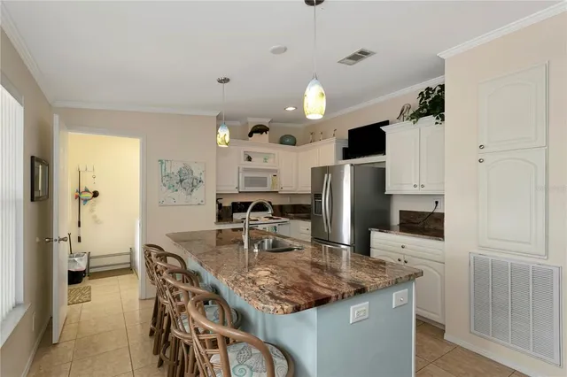 a kitchen with stainless steel appliances kitchen island granite countertop a table chairs and a refrigerator