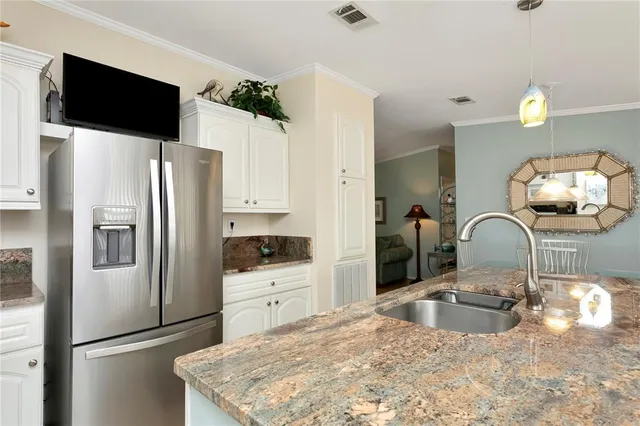 a kitchen with stainless steel appliances granite countertop a refrigerator a stove a sink and a white cabinets