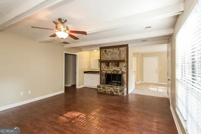 a view of a livingroom with a flat screen tv wooden floor and a ceiling fan