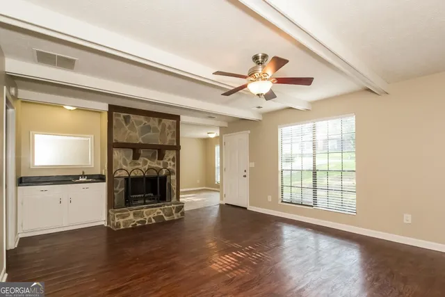 an empty room with wooden floor a fireplace and windows