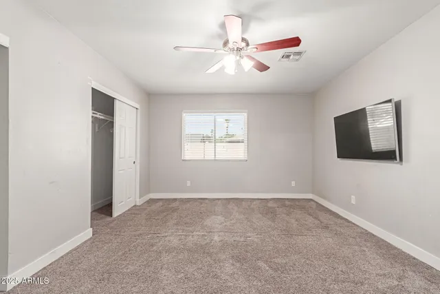 an empty room with windows and fan