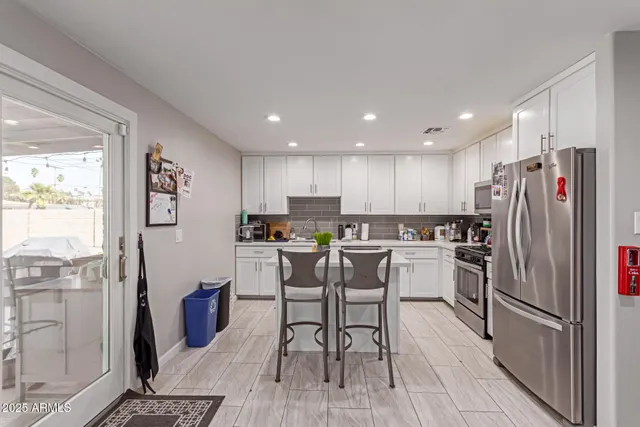 a kitchen with stainless steel appliances a refrigerator a stove a sink dishwasher and a dining table with wooden floor