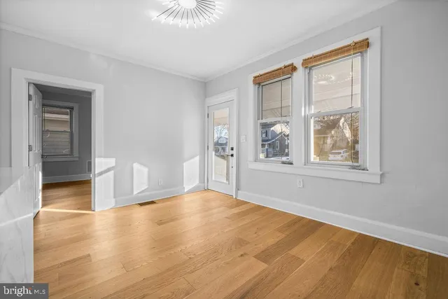 a view of an empty room with window and wooden floor