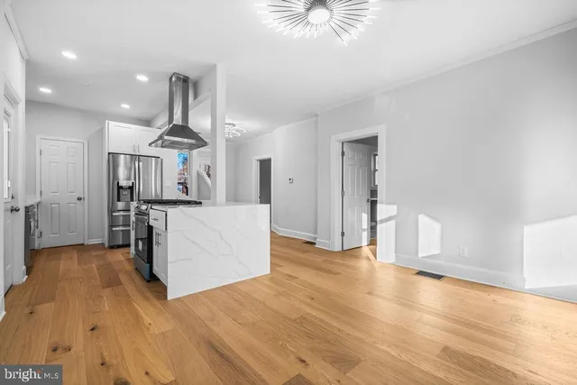 a view of a kitchen with kitchen island wooden floor stainless steel appliances and cabinets