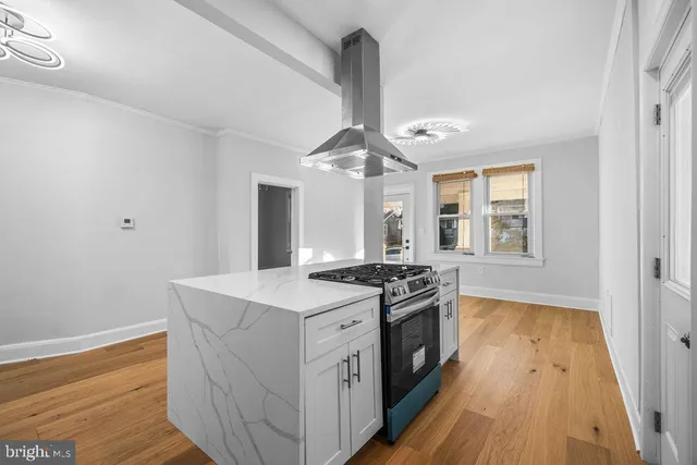 a kitchen with a stove and wooden floor