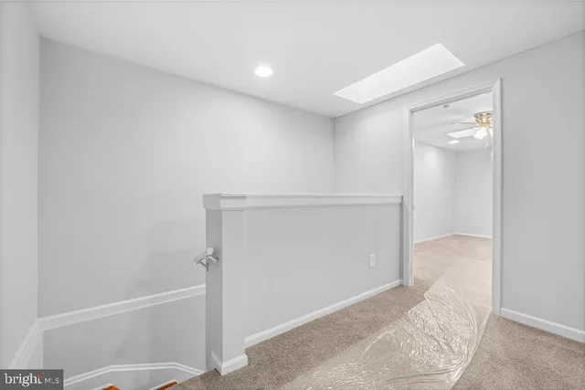 en empty room with windows and chandelier fan