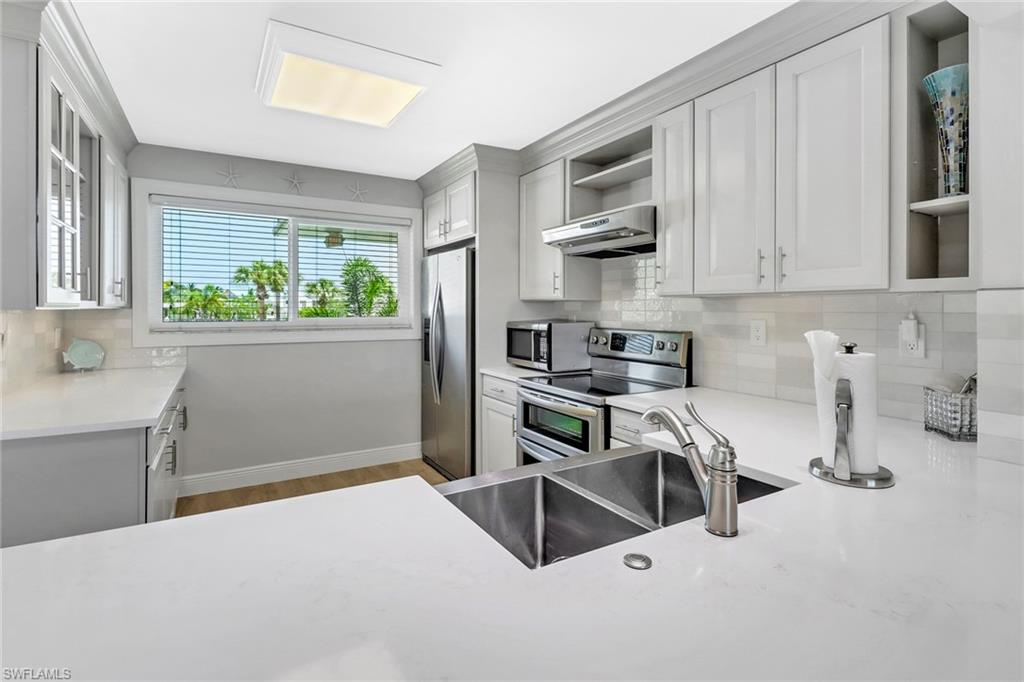 305 Goodlette Road South, Unit C302 Naples, FL 34102 - Photo 4 of 22 a kitchen with stainless steel appliances a stove a sink a microwave and cabinets