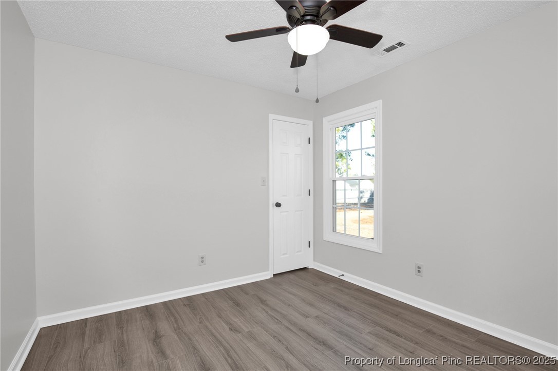 501 Camden Road Raeford, NC 28376 - Photo 21 of 35 an empty room with wooden floor ceiling fan and windows