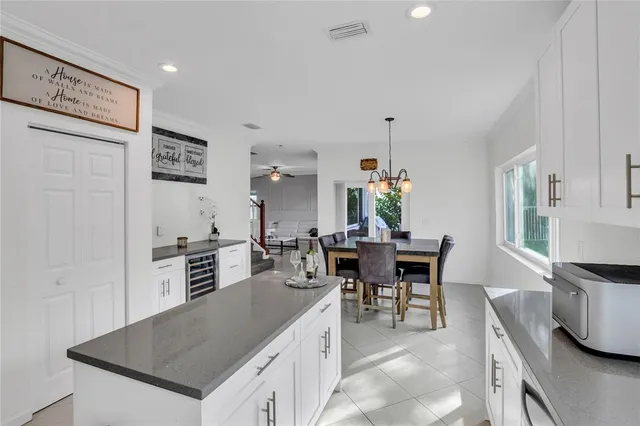 a kitchen with stainless steel appliances granite countertop a stove top oven a sink a dining table and chairs with white cabinets