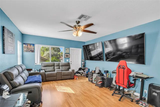 a living room with furniture a flat screen tv and a floor to ceiling window