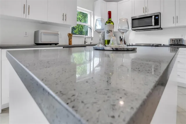 a kitchen with granite countertop a sink a stove top oven a counter top space and cabinets