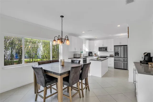 a kitchen with a dining table chairs and refrigerator