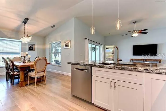 a kitchen with stainless steel appliances granite countertop a stove a sink a dining table and chairs