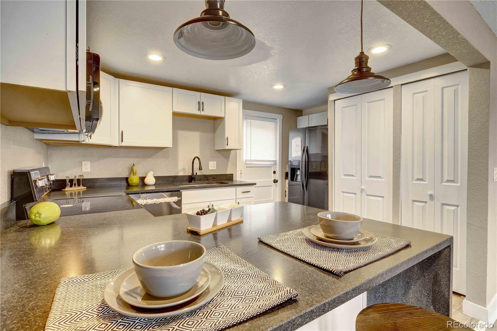 154 South Stuart Street Denver, CO 80219 - Photo 11 of 26 a kitchen with a stove a sink and a dining table with wooden floor