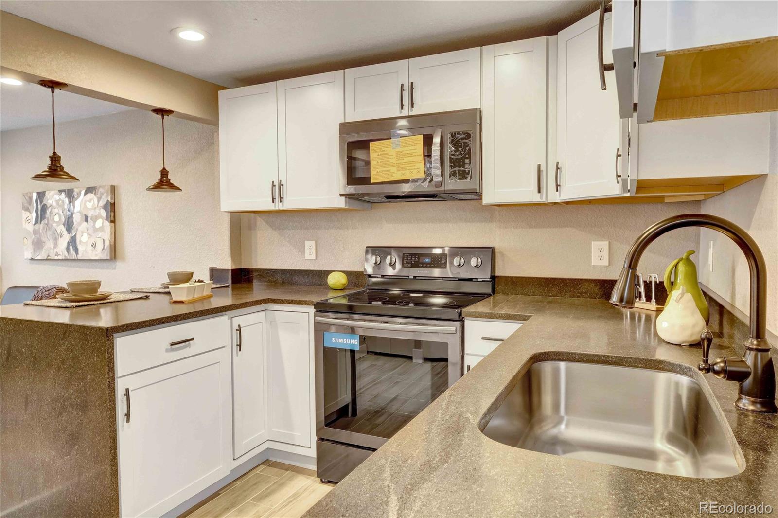 154 South Stuart Street Denver, CO 80219 - Photo 13 of 26 a kitchen with granite countertop a sink a stove and cabinets