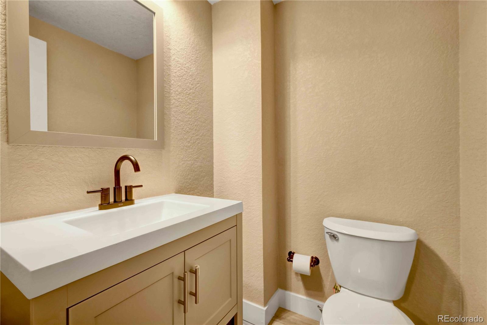 154 South Stuart Street Denver, CO 80219 - Photo 25 of 26 a bathroom with a sink a toilet and a mirror