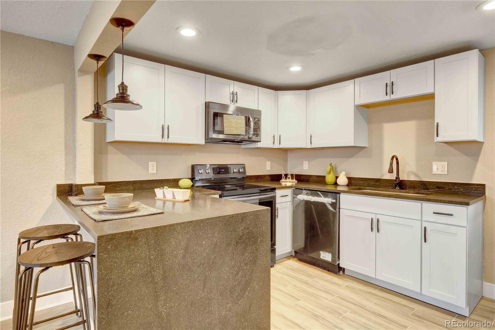 154 South Stuart Street Denver, CO 80219 - Photo 8 of 26 a kitchen with a sink a stove a microwave and wooden cabinets