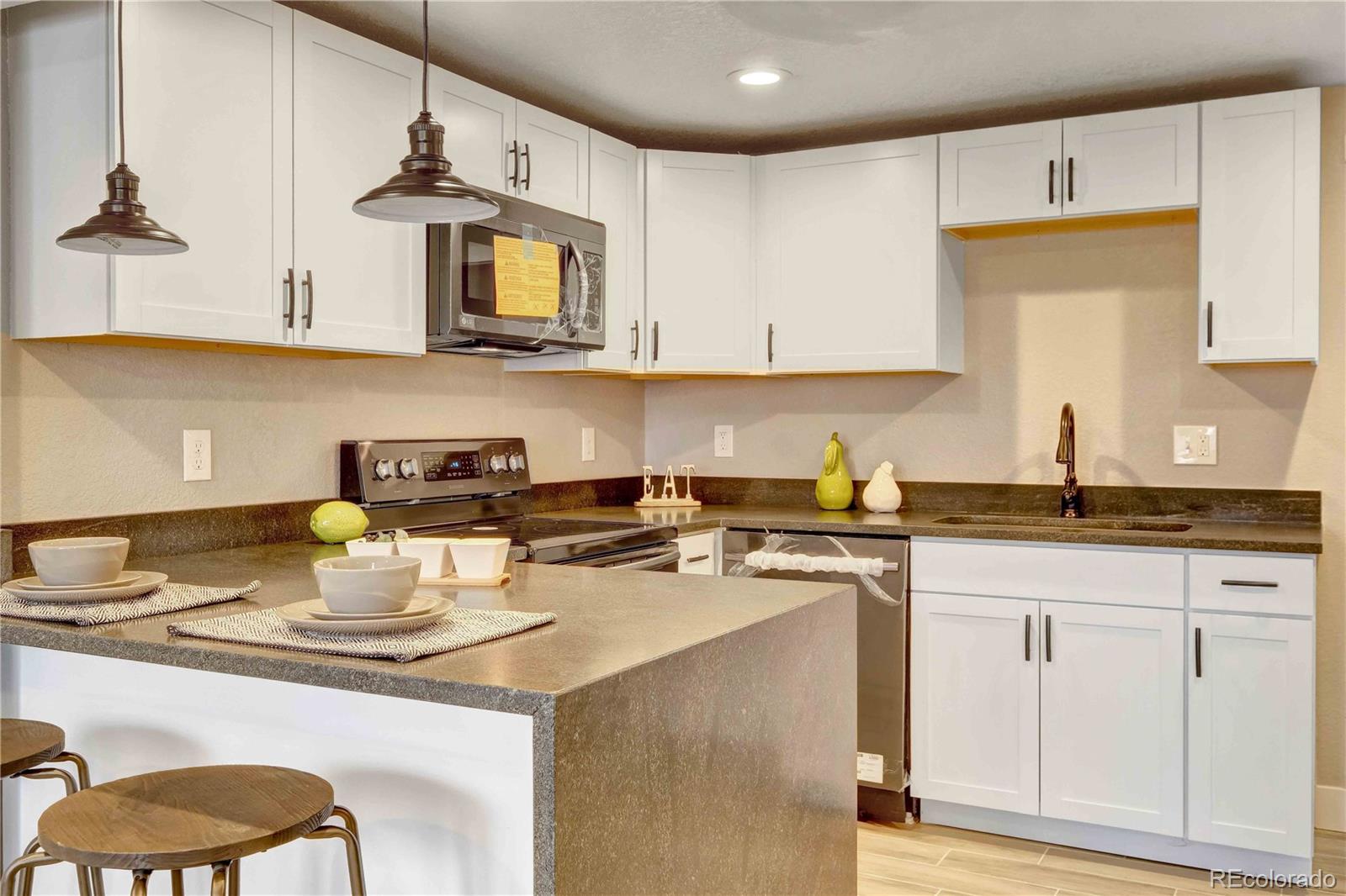 154 South Stuart Street Denver, CO 80219 - Photo 9 of 26 a kitchen with stainless steel appliances granite countertop a sink a stove and a microwave