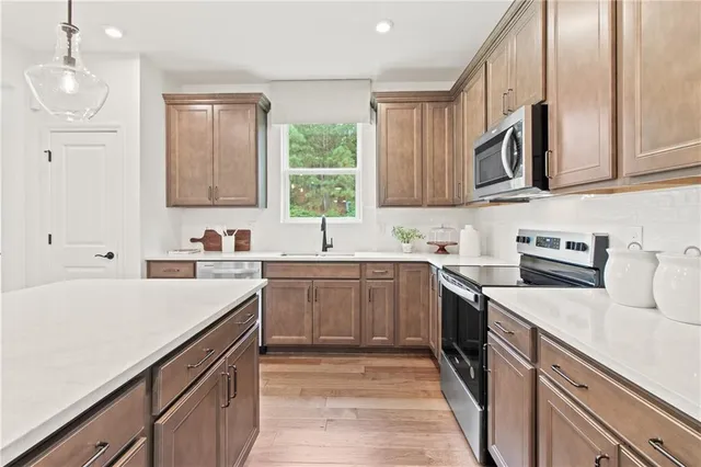 a room with stainless steel appliances kitchen island granite countertop a table chairs and a sink