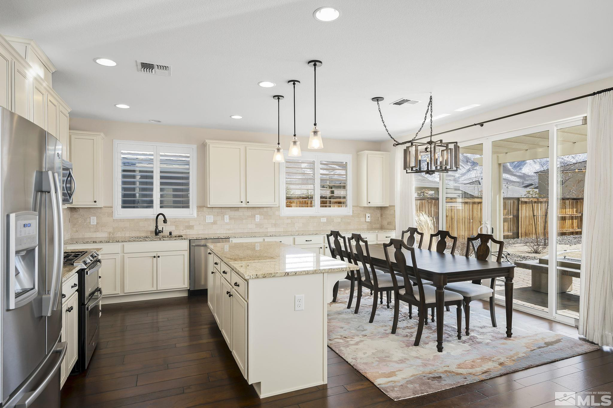 2860 Bonfire Lane Reno, NV 89521 - Photo 8 of 25 a large kitchen with kitchen island granite countertop a dining table chairs and white cabinets