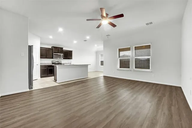 a view of a kitchen with a dishwasher a kitchen island hardwood floor and a ceiling fan