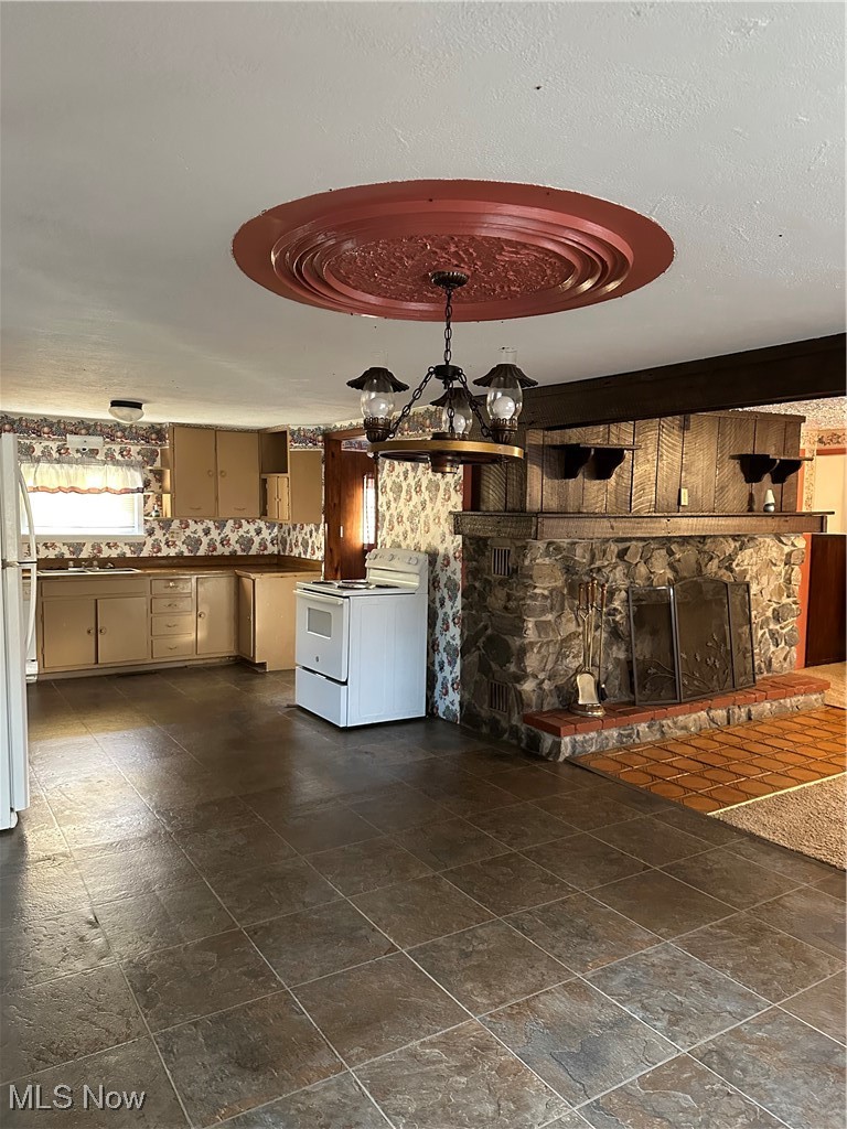 44952 Moose Ridge Road Woodsfield, OH 43793 - Photo 21 of 48 Kitchen with stove, a stone fireplace, pendant lighting, and refrigerator