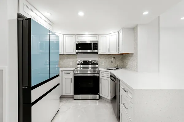 a kitchen with stainless steel appliances granite countertop a stove a sink and a refrigerator