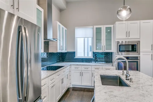 a kitchen with granite countertop a sink a counter space appliances and cabinets