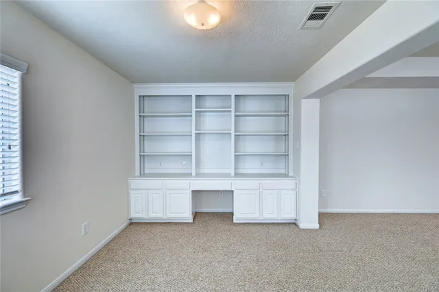 a view of an empty room with a fireplace and cabinet