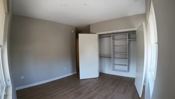a view of an empty room with wooden floor and closet