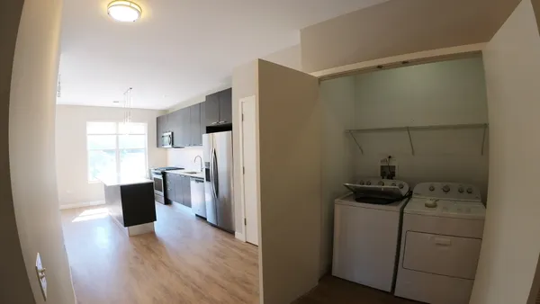 a view of a kitchen with refrigerator and wooden floor