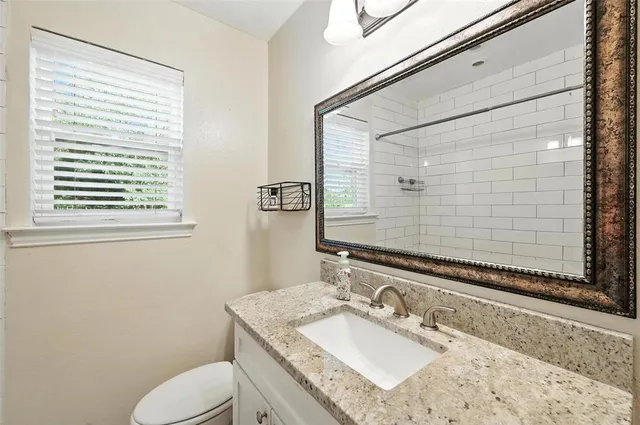 a bathroom with a granite countertop sink a mirror and shower