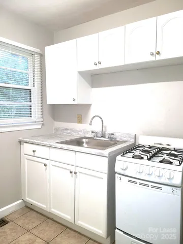 a kitchen with granite countertop a sink stove and cabinets