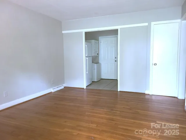 a view of an empty room with wooden floor and closet