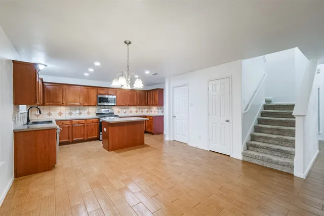 a kitchen with stainless steel appliances kitchen island wooden cabinets and chandelier