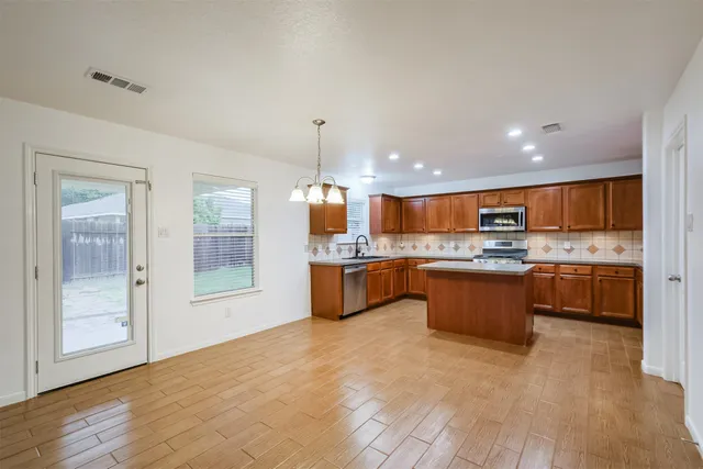 a large kitchen with a large counter top a sink stainless steel appliances and cabinets