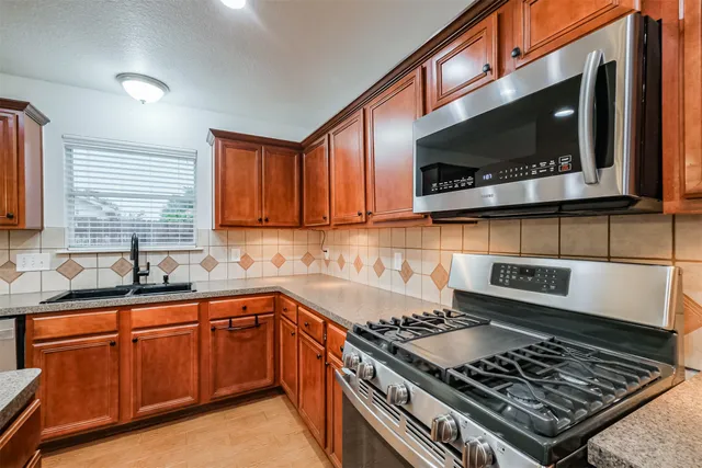 a large kitchen with a sink and dishwasher a stove top oven with wooden floor