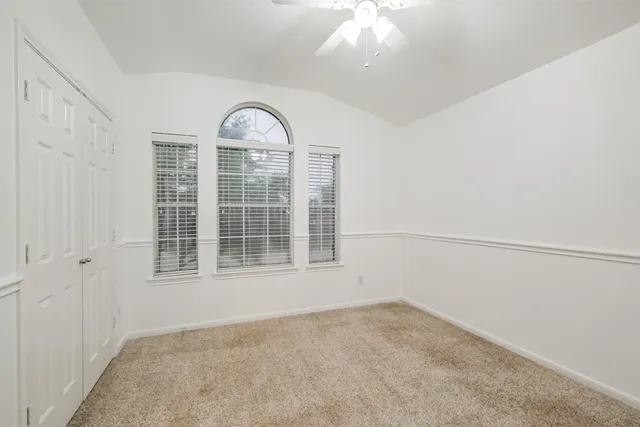 an empty room with a fan & a ceiling fan