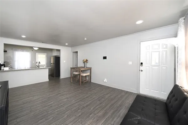 a view of an empty room with wooden floor and a kitchen