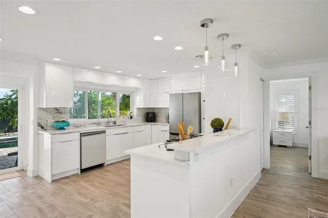 a room with kitchen island a white counter top space a sink a refrigerator and a view of living room