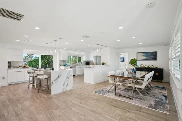a living room with couches and kitchen view with wooden floor