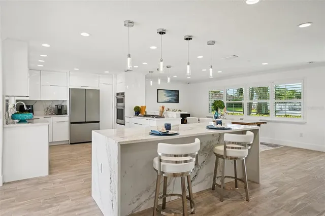 a kitchen with stainless steel appliances kitchen island granite countertop a sink and a refrigerator