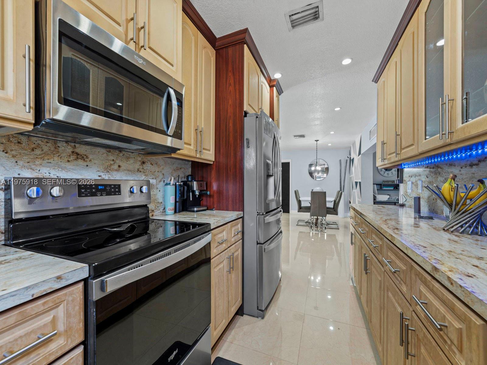 30236 Southwest 148th Place Homestead, FL 33033 - Photo 11 of 69 a kitchen with stainless steel appliances kitchen island granite countertop a stove a sink and a microwave