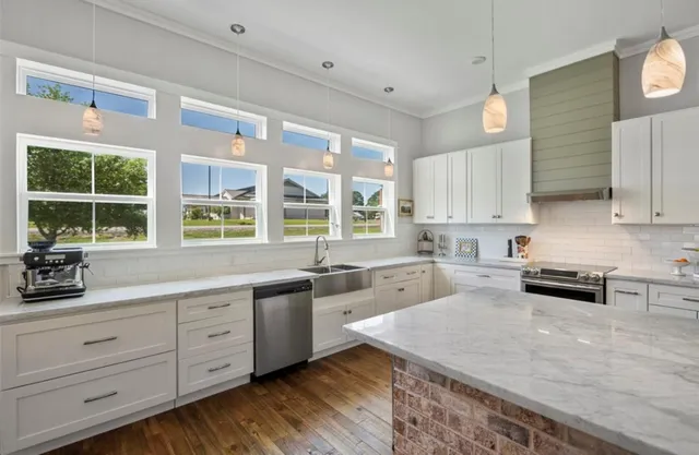 a kitchen with stainless steel appliances kitchen island granite countertop a stove a sink and white cabinets