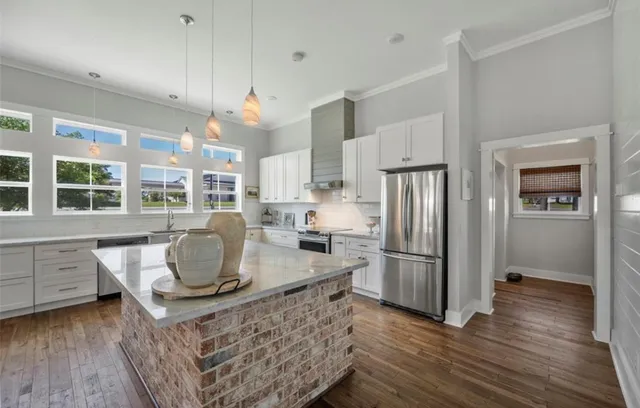 a kitchen with stainless steel appliances granite countertop a refrigerator a sink dishwasher a stove and a dining table with wooden floor