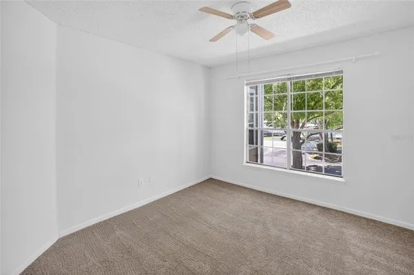 an empty room with windows and fan view