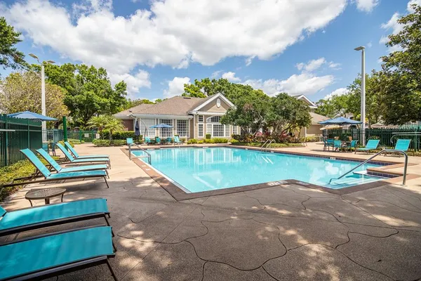 a view of swimming pool with lounge chair and dinning table under an umbrella
