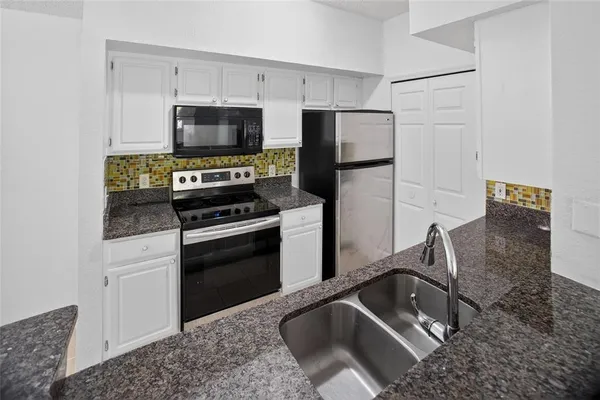 a kitchen with granite countertop a refrigerator stove and microwave