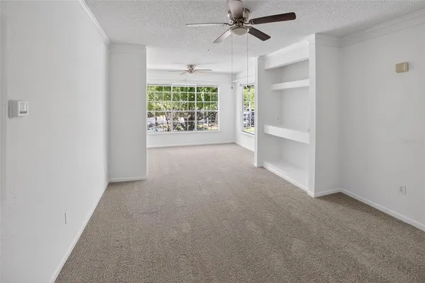 an empty room with windows and fan