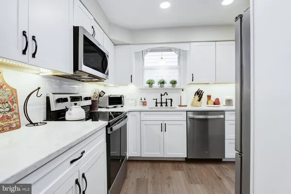 a kitchen with stainless steel appliances a sink a stove a microwave and cabinets